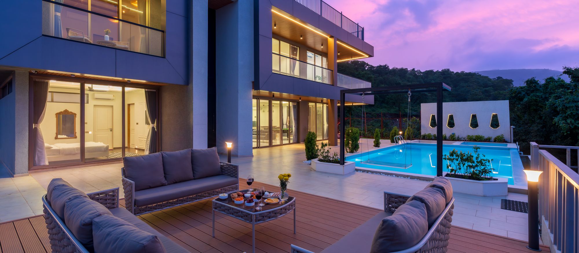 Modern home with a lit pool terrace at dusk