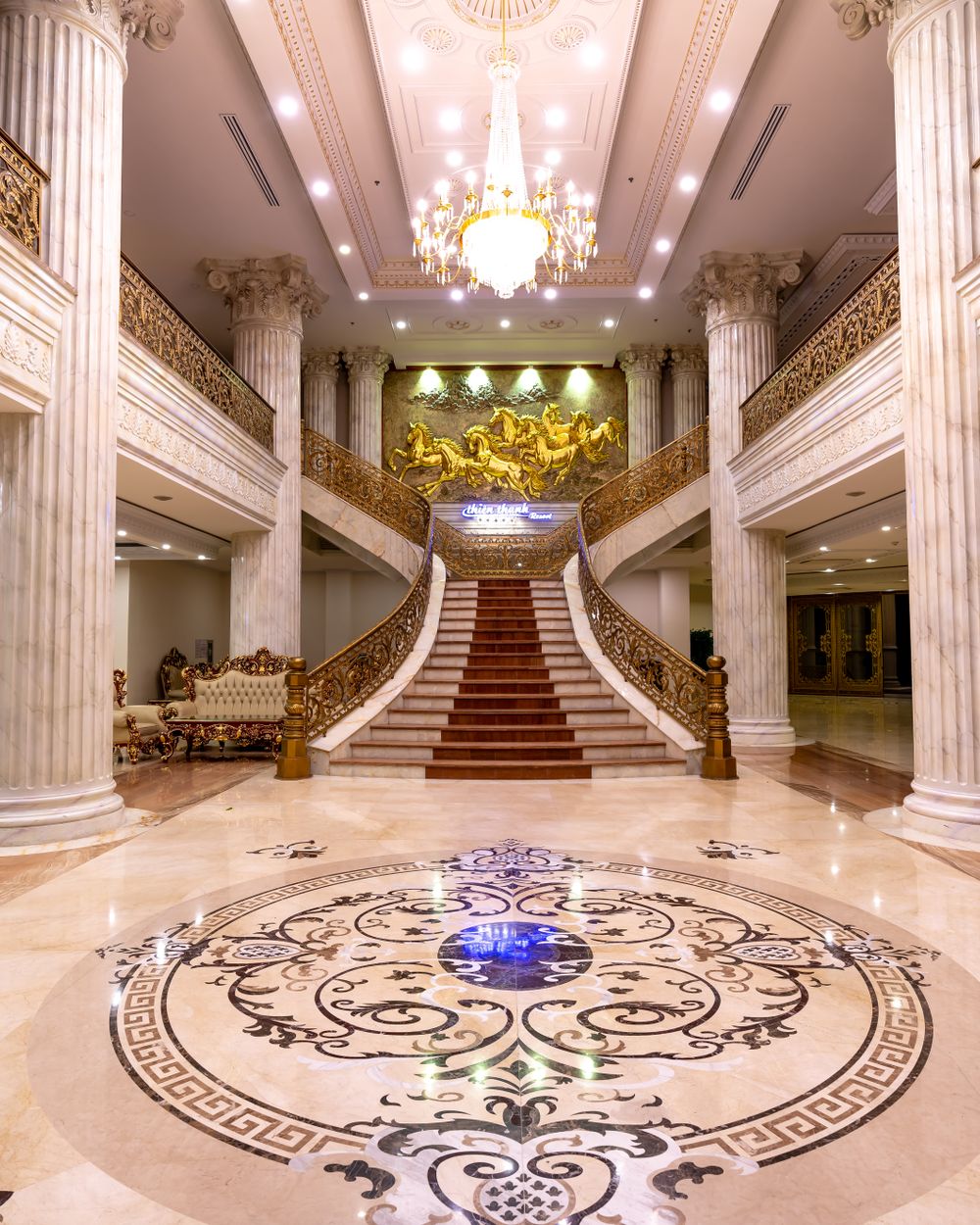 Hotel lobby with marble floors, columns and a grand staircase