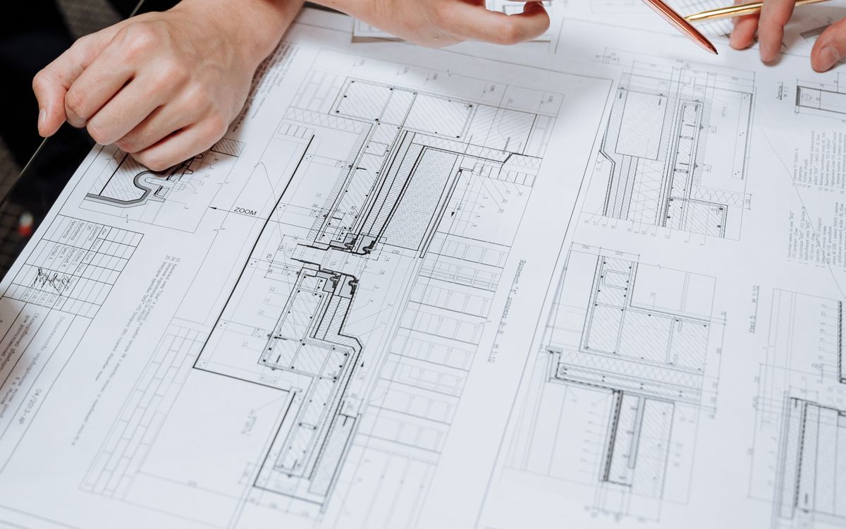 Two people reviewing detailed construction drawings on a table
