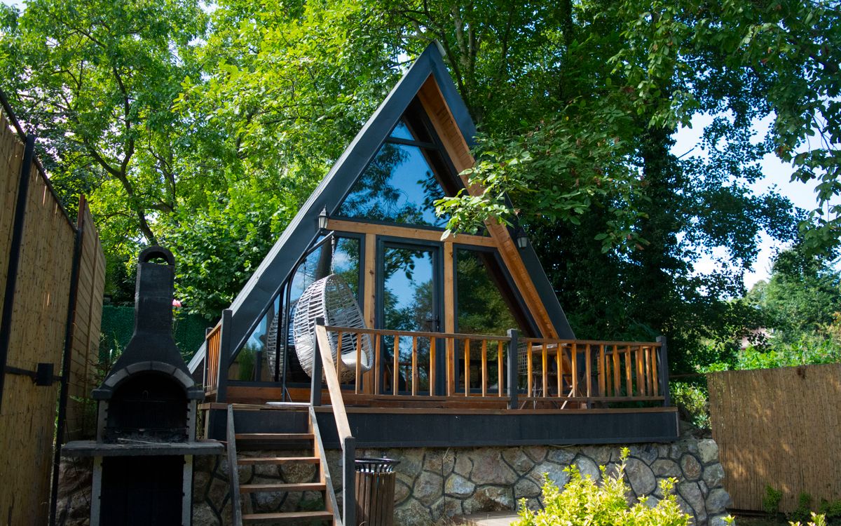 A-frame garden cabin with full-height glazing among trees