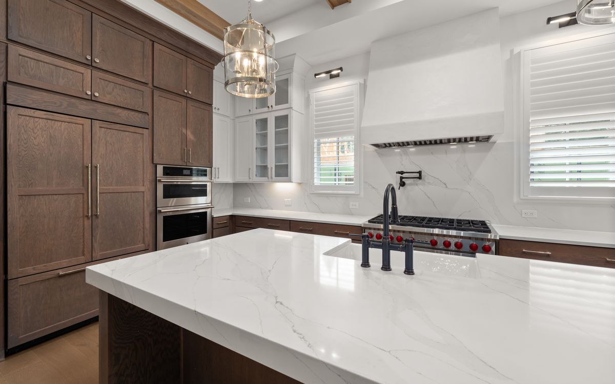 Renovated kitchen with a marble island and warm wood cabinetry
