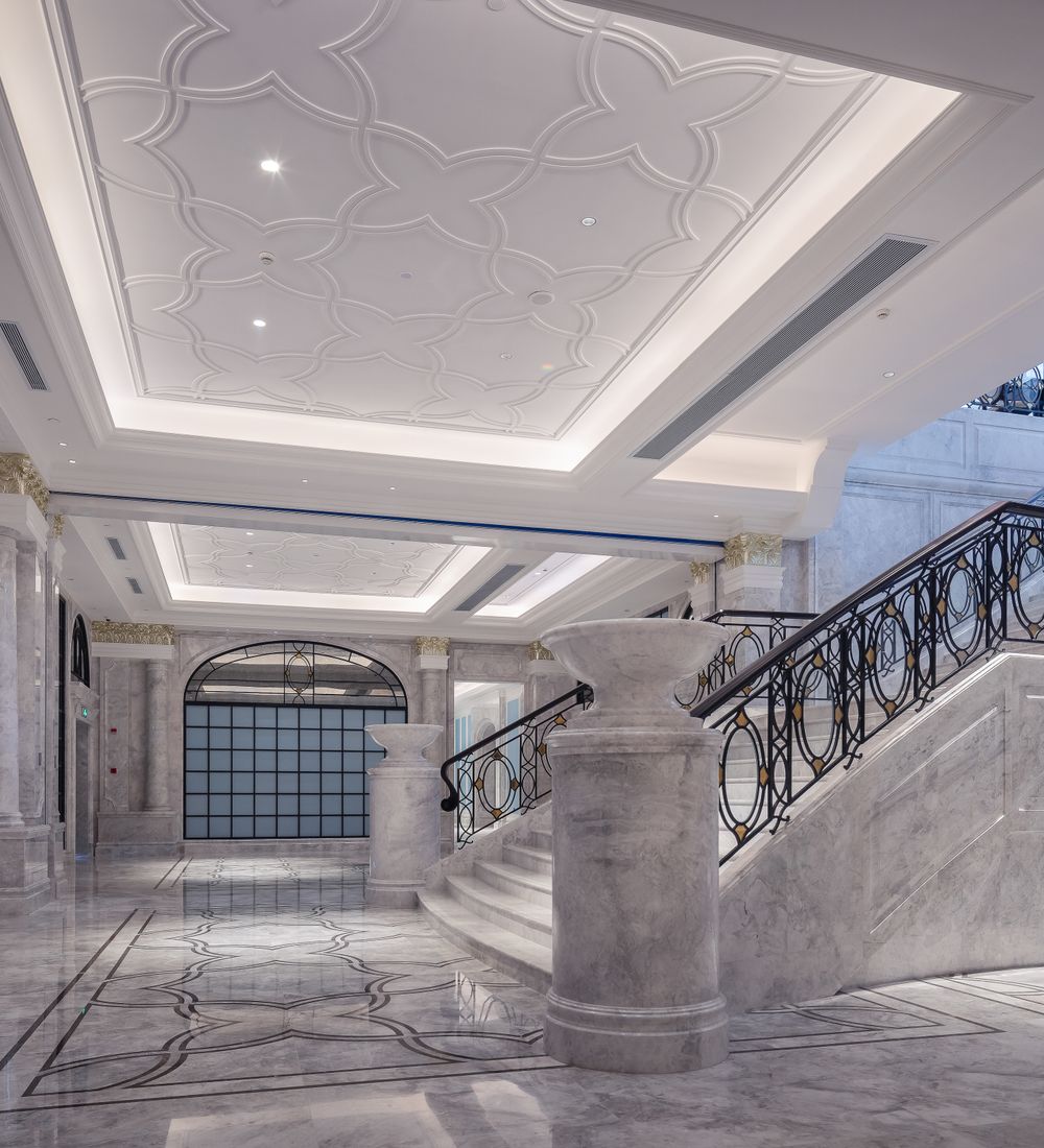 Marble-lined hallway with a curved staircase and coffered ceiling